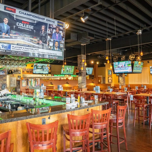 Timothy's Lionville interior with a bar, dining tables, chairs, and multiple TVs showing sports.