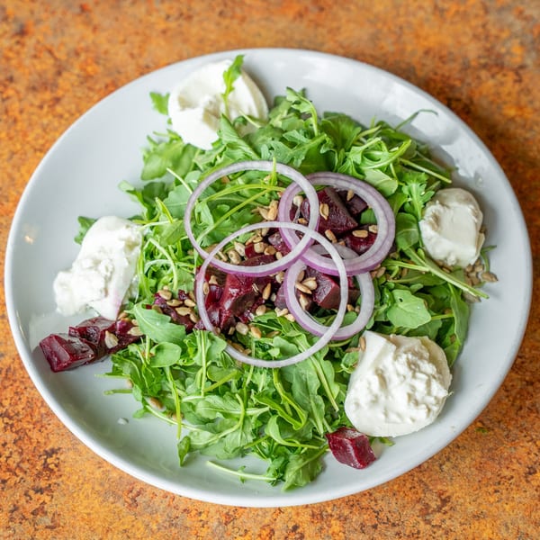 Arugula salad with beets, red onion, sunflower seeds, and dollops of goat cheese.