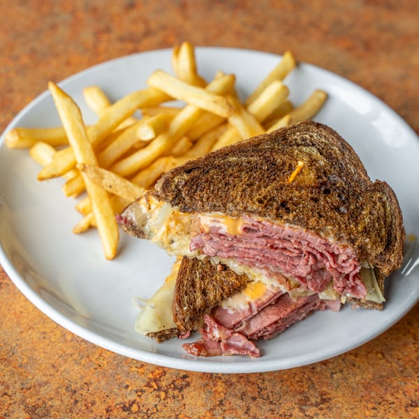 A Timothy's Lionville Reuben sandwich with corned beef, sauerkraut, and cheese, served with golden fries.