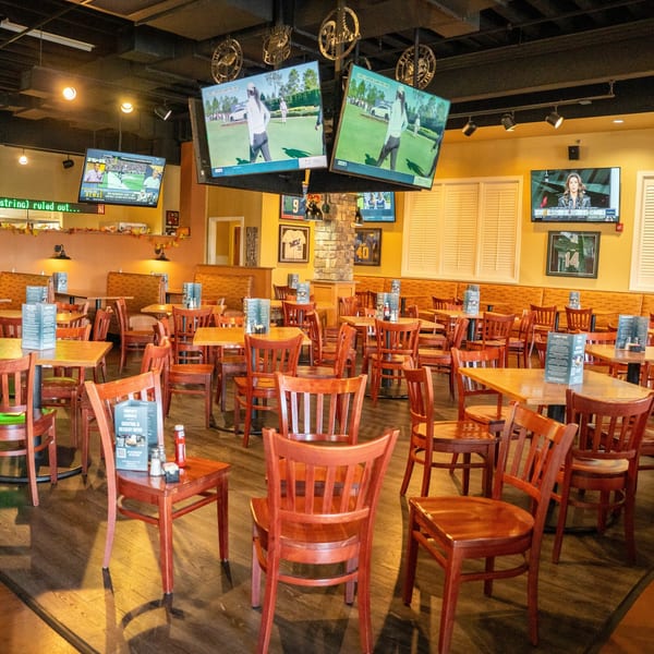 Timothy's Lionville dining room with many empty tables, chairs, and several TVs showing sports.