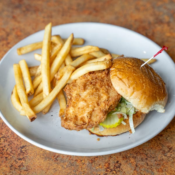 Crispy fried chicken sandwich with pickles and shredded lettuce, served with golden french fries.